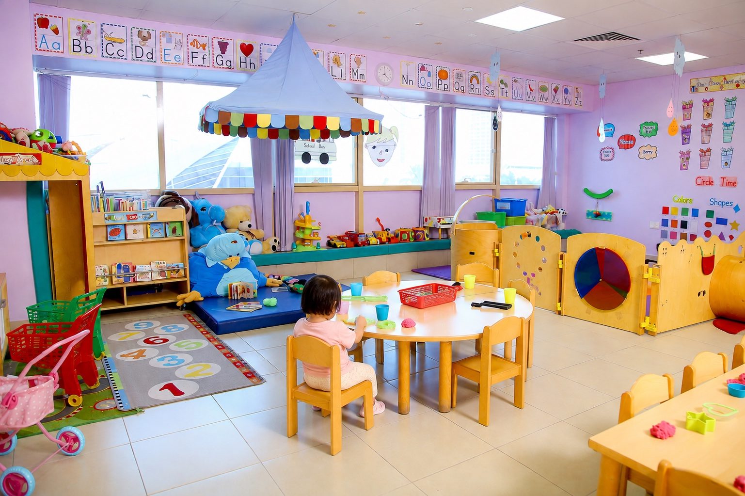 The Early Learners room at Mosaic, with a fabric play canopy, colourful low shelving, child-height tables and a wall of windows